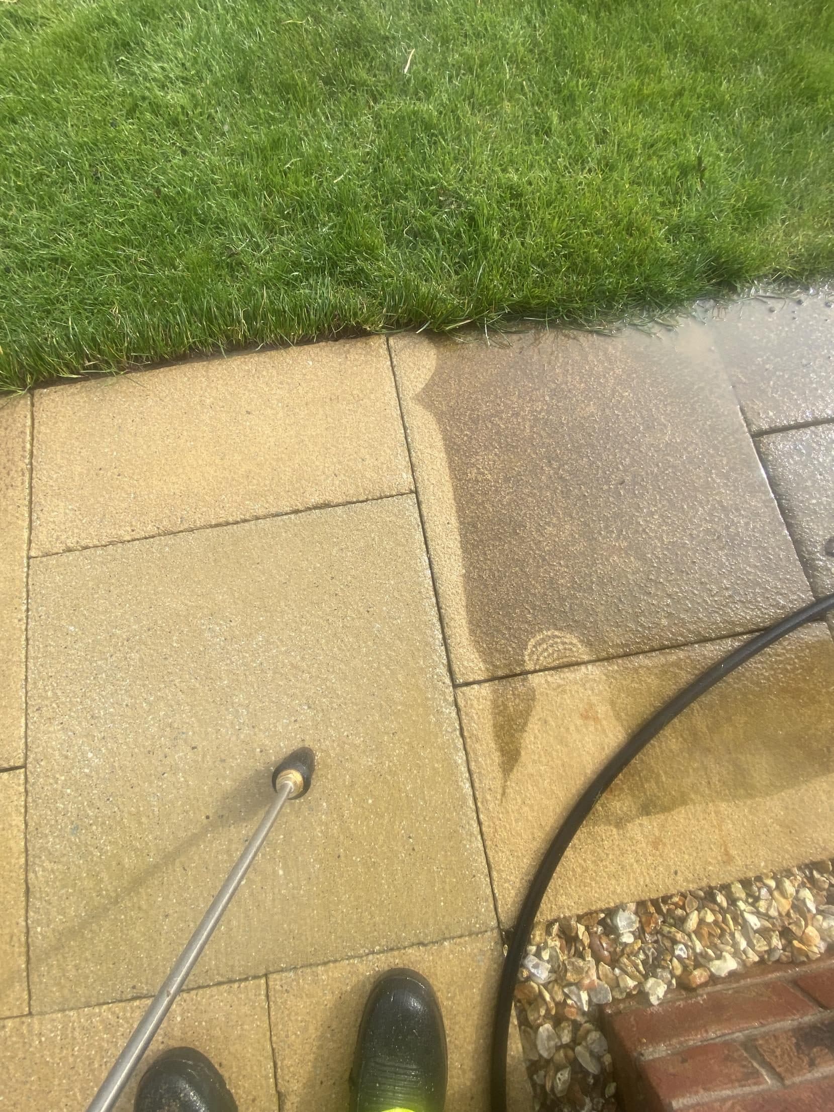 Patio being pressure washed, cleaned slabs next to dirty ones